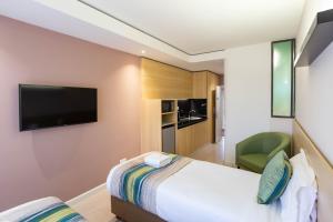 内罗毕Kozi Suites Nairobi Airport的配有一张床和一台平面电视的酒店客房