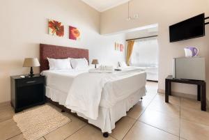约翰内斯堡Casas Navio Guest House的卧室配有一张白色大床和电视。