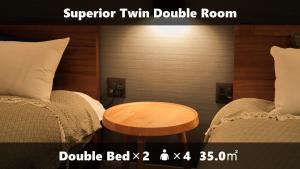 福冈Vieuno Stay Hakata 1的客房设有两张床和一张木桌。