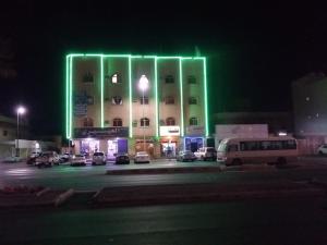 哈伊勒العييري للشقق المفروشة حائل 4的一座在晚上有绿灯的大建筑