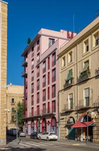 塔拉戈纳Tgna Reial 1的一座粉红色的建筑,前面有汽车停放