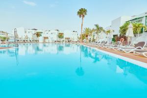 卡门港凯莱伊左洛俱乐部酒店的一个带椅子和棕榈树的大型游泳池