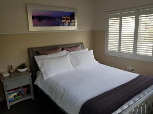 科莱特Waterfront Location - 2 Bed Apartment in Corlette, Port Stephens - Sleeps 4的一间卧室配有一张带白色床单的床和一扇窗户。