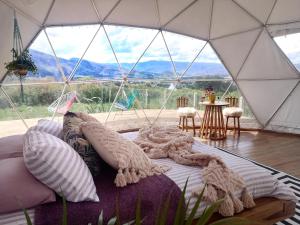 莱瓦镇Amatea de Villa de Leyva的一张位于帐篷内的床位,享有桌子的景色