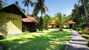 特贾库拉Camplung Beach Villa Tejakula with 6 Bedrooms and Pool的棕榈树庭院和房屋