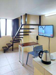 马尼拉airobedz MANILA - near Taft Avenue的客房设有桌子、电视和楼梯。