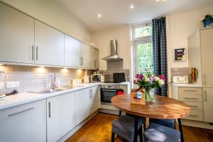 约克Middlethorpe Manor - No 6 Tranquility & Ease的厨房配有白色橱柜和花卉木桌
