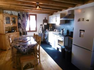 PuyvaladorLe logis des cerfs的厨房配有桌子、炉灶和冰箱。