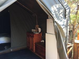 Hartebeest RivierOtium Oasis Glamping & Camping的一间设有冰箱和一张帐篷床位的房间