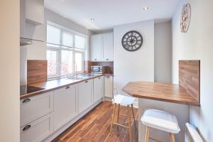 TotleyHost & Stay - Baslow Road, Serviced Apartment的厨房配有白色橱柜和木制台面