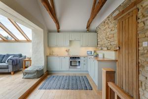 PerranwellThe Home Barn at Cornish Barn Holidays的一间设有蓝色橱柜的厨房和一间客厅