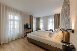 美因茨Hof Ehrenfels的酒店客房设有一张大床和两个窗户。