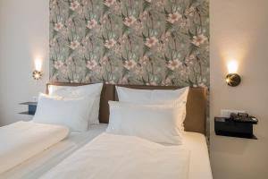 美因茨Hof Ehrenfels的一张带两个白色枕头和花卉壁纸的床
