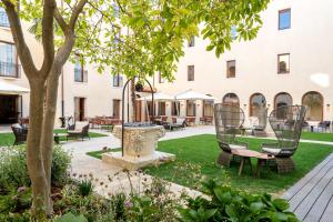 威尼斯Ca'di Dio-Small Luxury Hotel的建筑前的庭院,庭院里摆放着椅子和一棵树