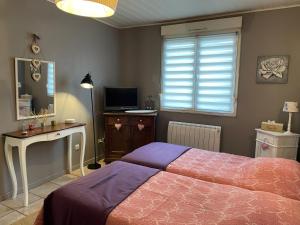 圣阿沃尔德Jardin Secret au Cœur de la Dourd’halie的一间卧室配有一张床、一张书桌和一台电视