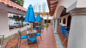 曼塔Hotel Voyager Manta的一个带蓝色桌椅和遮阳伞的庭院