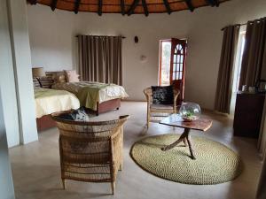 蓬戈拉Somkhanda Game Reserve的卧室配有一张床和一张桌子及椅子