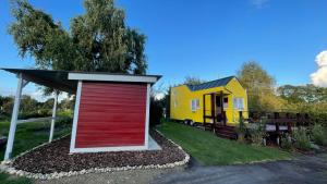 VisselhövedeFerienhaus Tiny Löwenzahn的一间小房子旁边的一个黄色和红色车库