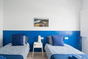 普拉亚布兰卡Blancazul Harbour View的蓝色墙壁客房的两张床