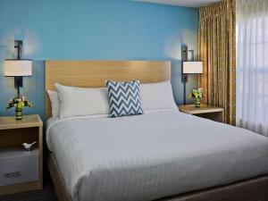 切斯特菲尔德Sonesta ES Suites St. Louis - Chesterfield的一间卧室配有一张大床、蓝色的墙壁和两盏灯。