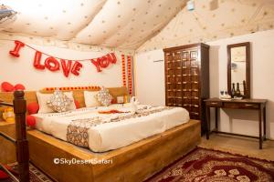 山姆Sky Desert Safari & Spa的卧室配有一张挂有爱情标志的床
