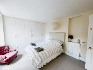 肯德尔SUNNYSIDE APARTMENT - Spacious 2 Bedroom Ground Floor with Free Parking In Kendal, Cumbria的白色卧室配有床和粉红色椅子