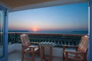 帕纳吉海滨露台酒店的阳台上配有两把椅子和一张桌子,享有日落美景