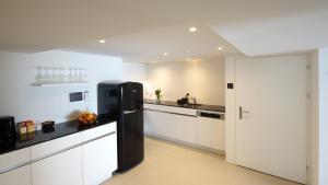阿彭策尔Alte Metzg - Hostel的厨房配有黑冰箱,厨房配有白色橱柜