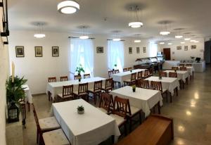 赛伦奇Huszárvár Hotel Kastélyszálló的一间设有白色桌椅的用餐室