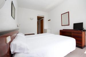 卡拉米洛米尔别墅酒店的一间白色卧室,配有床和电视