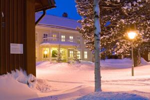 谢莱夫特奥Stiftsgården Hostel Skellefteå的一座有房子和树的雪地覆盖的院子