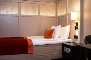 斯德哥尔摩Scandic Grand Central的酒店客房,配有一张带橙色枕头的床