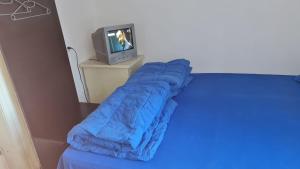 布什泰尼Camping Aviator Busteni, camere的一张带蓝色睡袋的床,毗邻电视