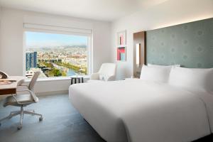 旧金山LUMA Hotel San Francisco - #1 Hottest New Hotel in the US 2023的一间卧室配有一张大床、一张书桌和一个窗户。