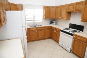 Long PathBreezee的厨房配有木制橱柜和白色冰箱。