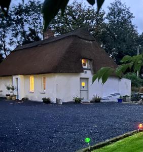 Cross of the TreeNew Thatch Farm, knocklong, Limerick的茅草屋顶房屋,带碎石车道