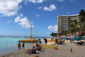 檀香山Aloha Suites Waikiki的一群人,在海滩上,有一条黄色的船