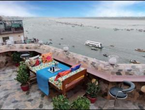 瓦拉纳西湿婆恒河景观旅馆的阳台配有桌子和椅子,毗邻水体