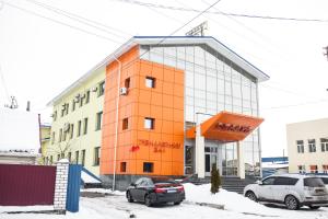 KorostyshivГотель Релакс的一座橙色的建筑,前面有汽车停放