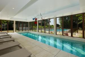 博讷Les Nomades Beaune的游泳池设有躺椅和窗户