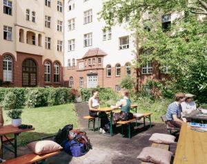 柏林Three Little Pigs Hostel - Your Berlin Castle的一群坐在庭院桌子上的人