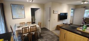 阿罗柴尔The Cobbler Cottage - Loch Lomond and Arrochar Alps的一间带桌子的客厅和一间带电视的厨房