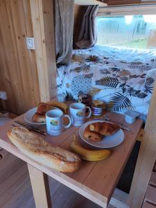 FouchèresLes Cabanes d'Hérande的桌子,上面放有面包盘和咖啡杯