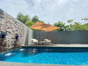 珍南海滩LeGrace Villa Langkawi Private Pool的游泳池旁配有遮阳伞的桌椅