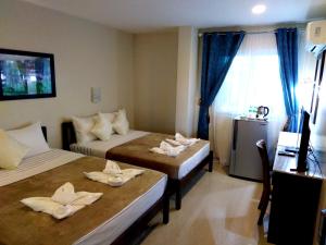 伊洛伊洛Venezia Suites Hotel Iloilo的客房设有两张床、一张桌子和一个窗户。