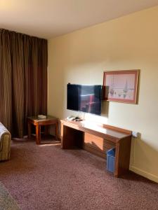 艾恩Top Hotel Apartments的酒店客房的书桌上配有平面电视