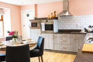 TurriffBramble Cottage的带餐桌的厨房和带粉红色墙壁的厨房