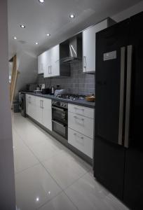 伯明翰Comfortable stay in Shirley, Solihull - Room 1的厨房配有白色橱柜和黑色冰箱。