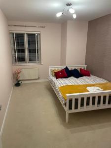 威布里治Luxurious & Cosy Apartment in Surrey的一间卧室配有一张带红色和蓝色枕头的床