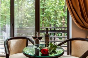 博托沙尼Rediu Hotel & Restaurant的一张桌子,上面放着两杯葡萄酒和一朵玫瑰